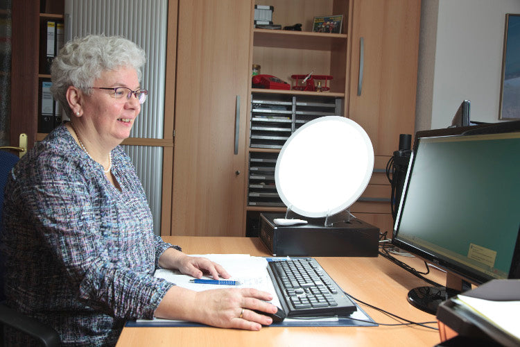 Frau arbeitet am Computer auf einem Schreibtisch mit dem Licht der Lena 400
