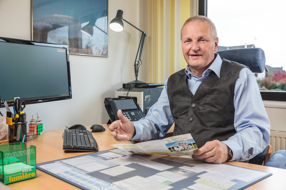 Mann sitzt am Schreibtisch im Hintergrund leuchtet die Tifez