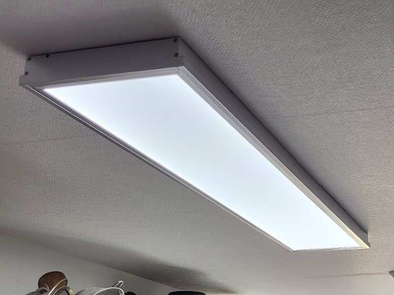 an einer Decke leuchtet ein LED Panel mit Rahmen
